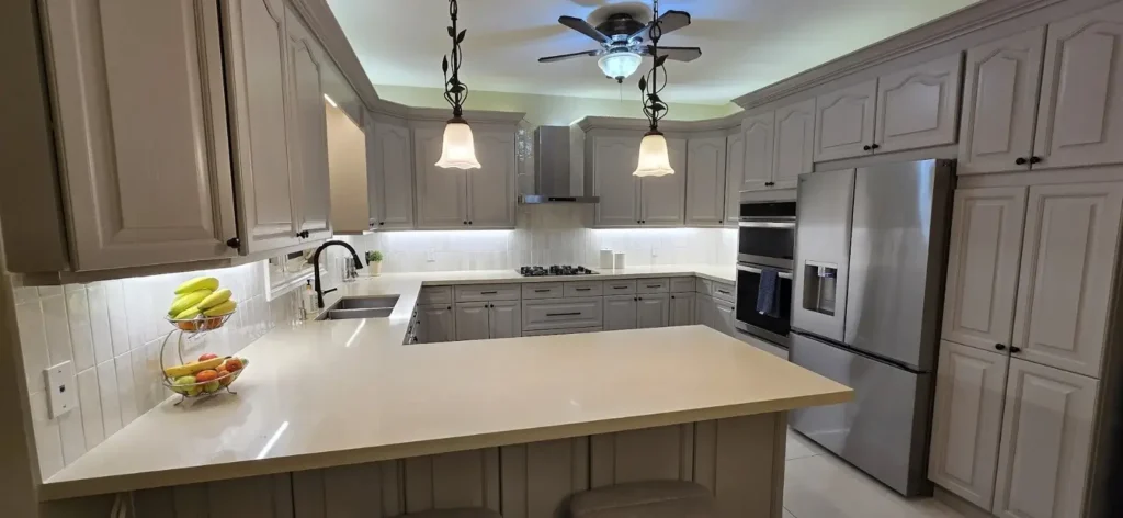 Grey raised panel traditional kitchen with white quartz countertops pendant lights and stainless appliances by MD Kitchen and Bath