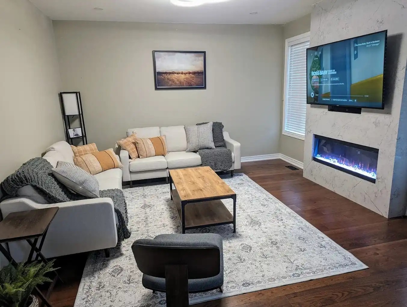 Modern living room with floor to ceiling Calacatta quartz electric fireplace feature wall wall mounted TV white sectional sofa wood and metal coffee table patterned area rug and dark hardwood floor