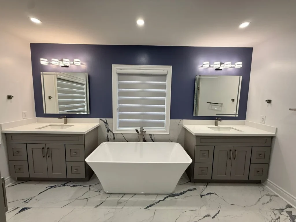 Master bathroom renovation with double grey vanity freestanding soaker tub and navy accent wall by MD Kitchen and Bath