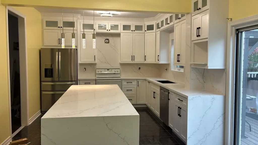 Wide angle view of white shaker kitchen with frosted glass uppers matte black hardware Calacatta quartz countertop and backsplash stainless French door fridge white range royal blue island and dark charcoal tile floor by MD Kitchen and Bath