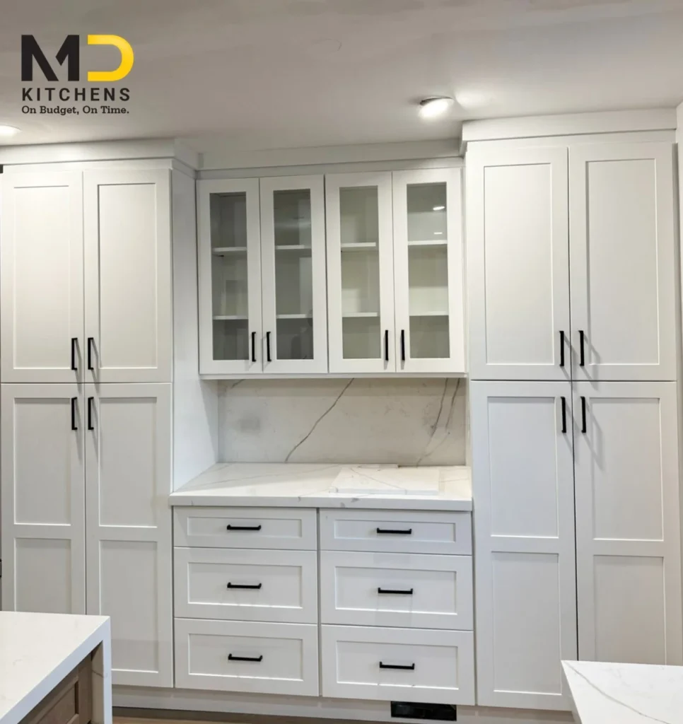 Front facing view of white kitchen pantry wall with dual full height pantry cabinets glass display uppers and Calacatta quartz by MD Kitchen and Bath