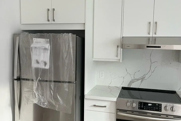 White flat panel kitchen with brand new stainless Whirlpool top freezer refrigerator stainless Frigidaire electric range stainless under cabinet hood and Calacatta quartz backsplash by MD Kitchen and Bath