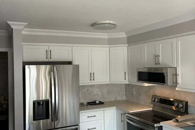 White shaker kitchen fridge wall with stainless French door refrigerator stainless built-in microwave brushed nickel bar pull hardware cloud grey quartz backsplash white quartz countertop crown molding and dark hardwood floor by MD Kitchen and Bath
