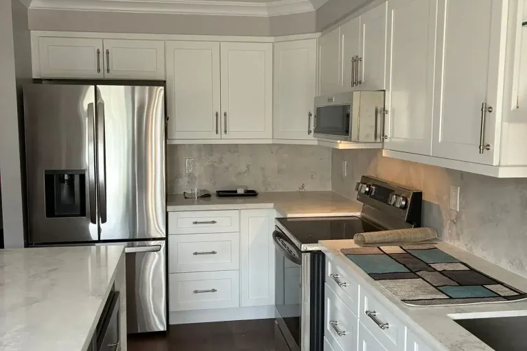 White shaker kitchen with brushed nickel hardware stainless French door fridge stainless electric range stainless built-in microwave cloud grey quartz backsplash white quartz countertop dark charcoal island and dark hardwood floor by MD Kitchen and Bath